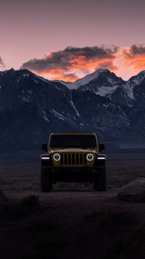 Yellow Jeep Wrangler in front of mountains at sunset 4K
