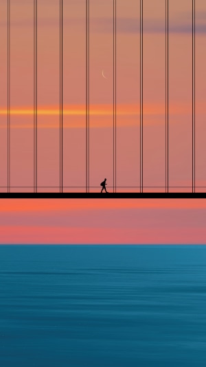 Silhouette of a person walking on a bridge at sunset