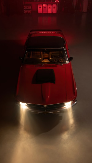 Red Ford Mustang with headlights on