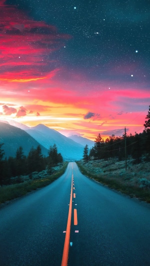 Road through mountains at sunset with stars