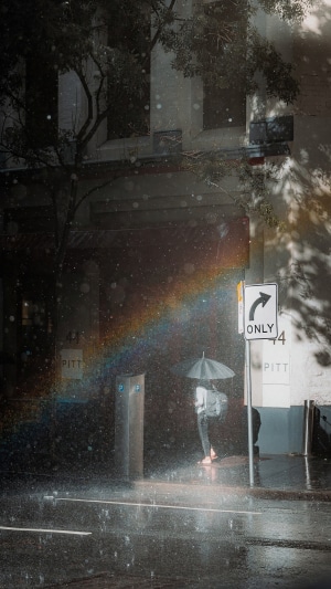 Person with umbrella in the rain with rainbow