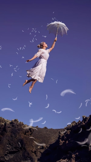 Woman flying with umbrella and feathers