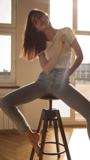 Woman in jeans and t-shirt sitting on stool