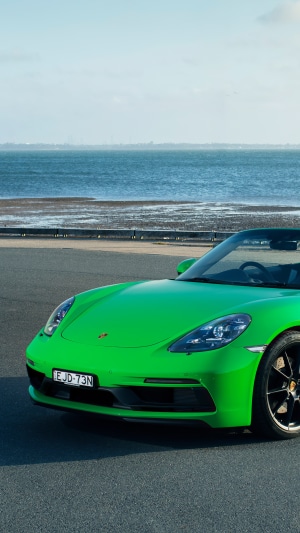 Green Porsche 718 convertible by the sea