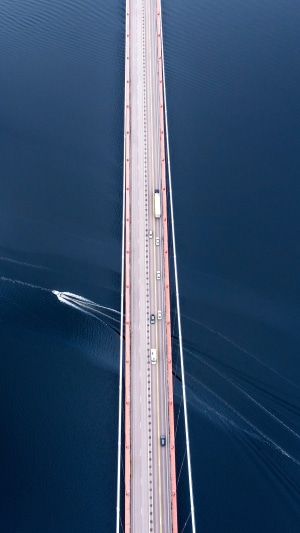 Aerial view of a suspension bridge with traffic and a boat