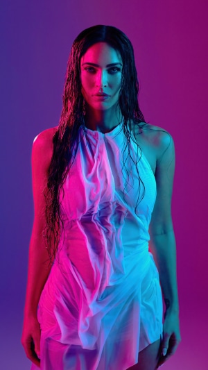 Megan Fox in a white dress under colored lights