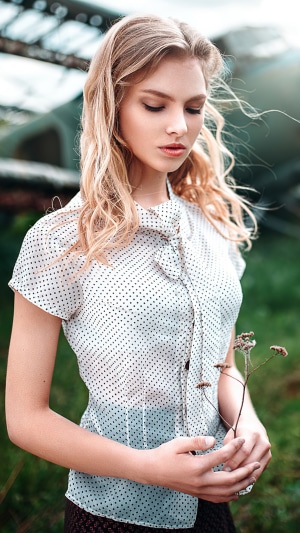 Blonde girl with polka dot shirt holding a plant