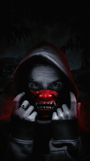 Person wearing a red oni mask and hoodie