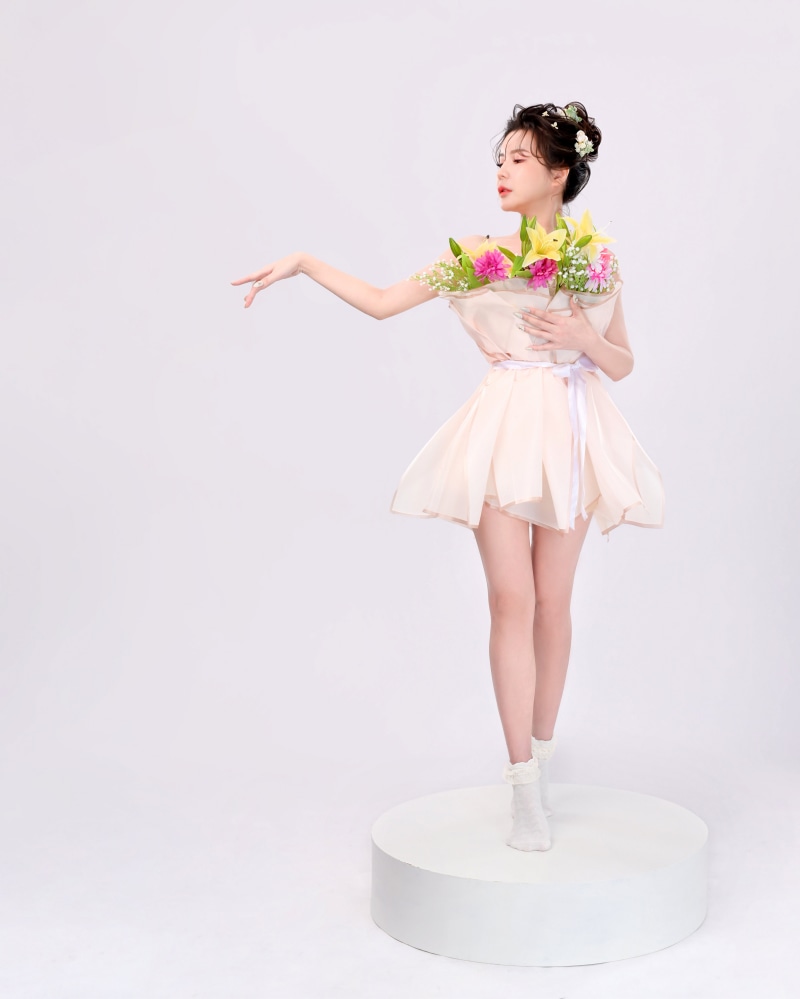 Asian woman in dress holding flowers on a white platform