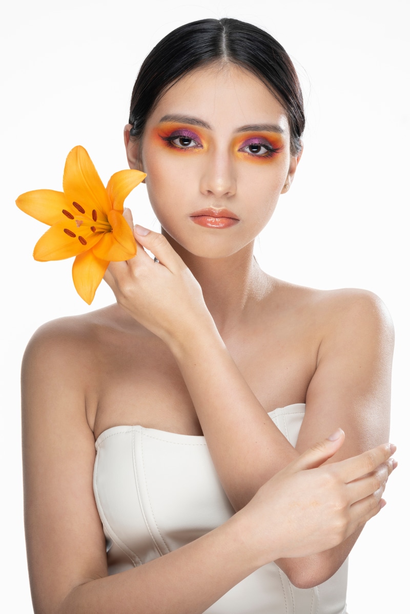Brunette girl with orange lily and makeup