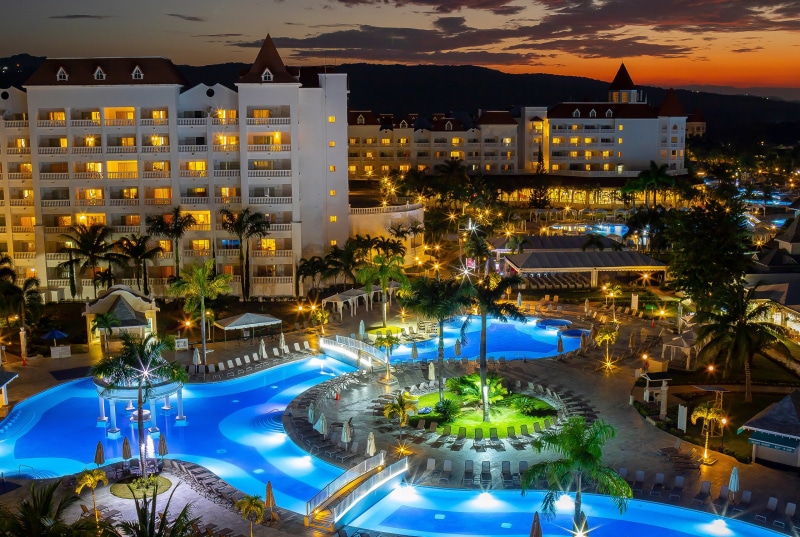 Resort with pools and palm trees at dusk