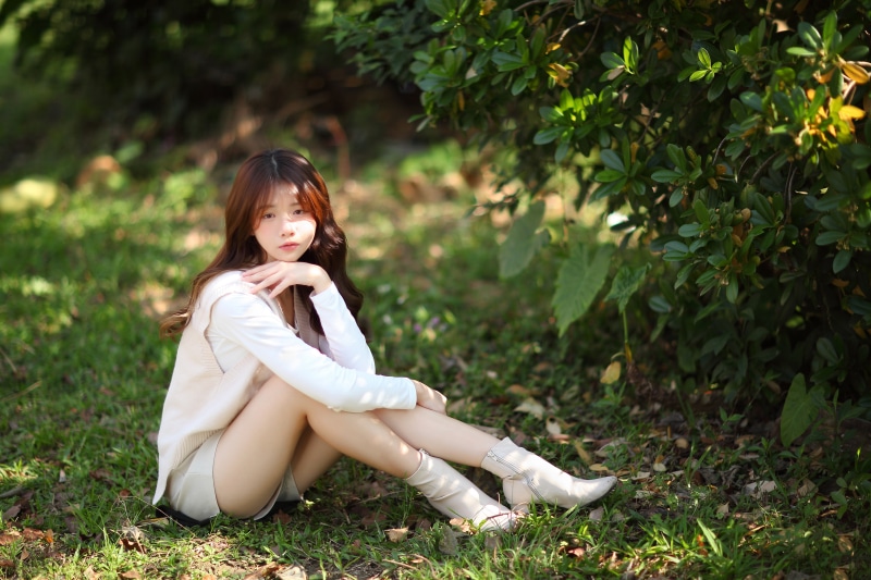 Asian woman sitting in grass wearing shorts and blouse