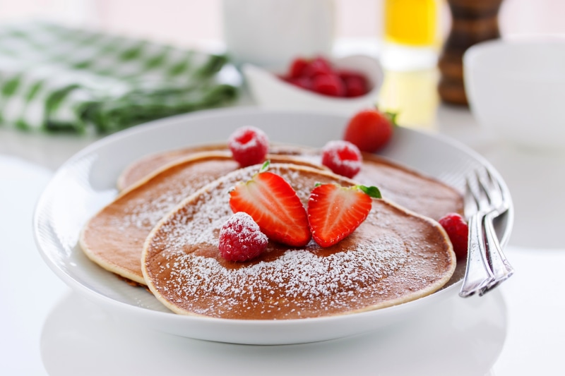 Pancakes with raspberries and strawberries, dusted with powdered sugar