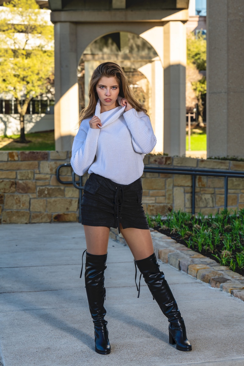 Woman wearing a sweater and skirt with boots