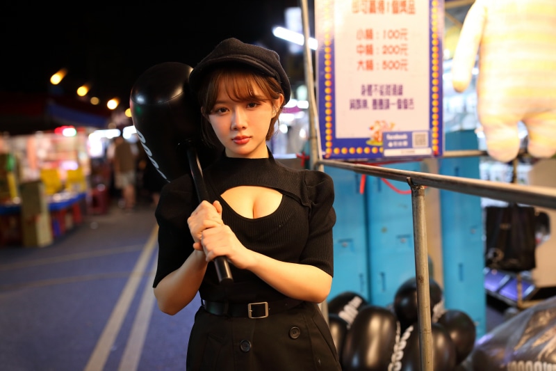 Asian woman in black dress and baseball cap