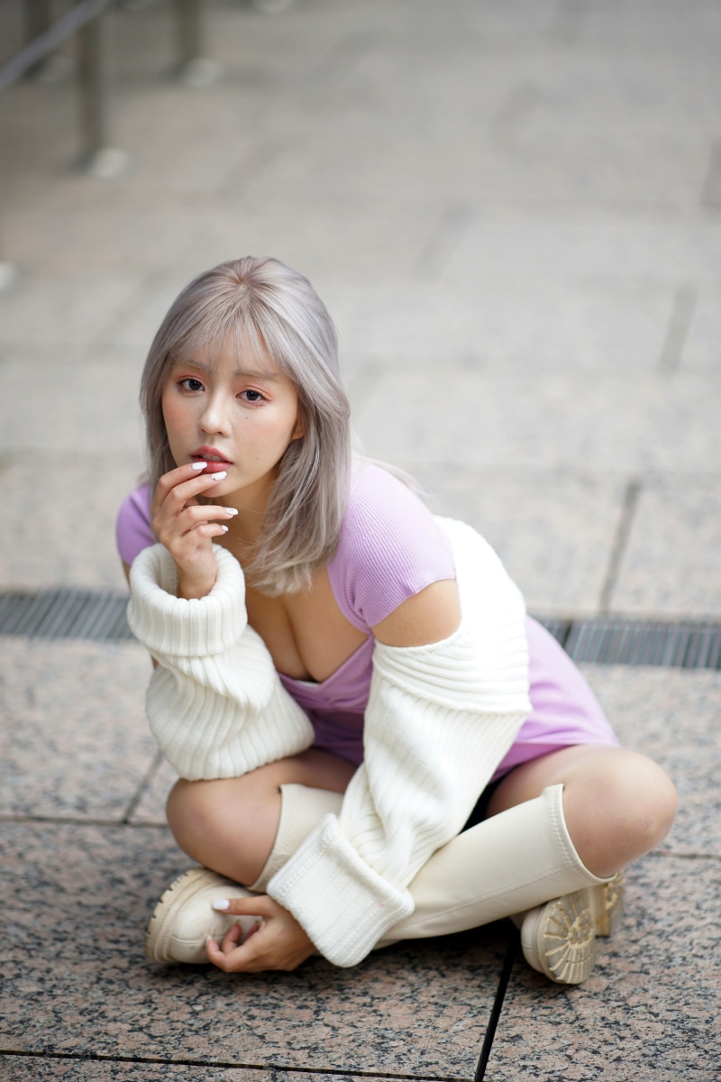 Asian woman in purple dress and white sweater sitting on the ground