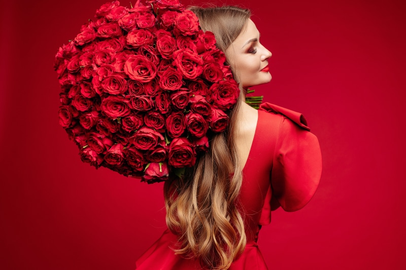 Woman in red dress holding bouquet of red roses