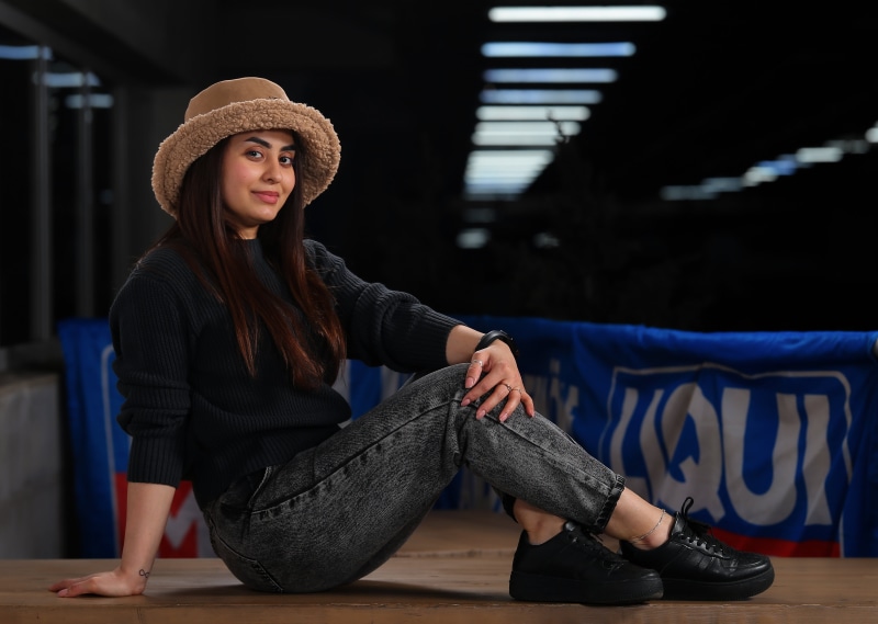 Woman in sweater, jeans, and hat sitting