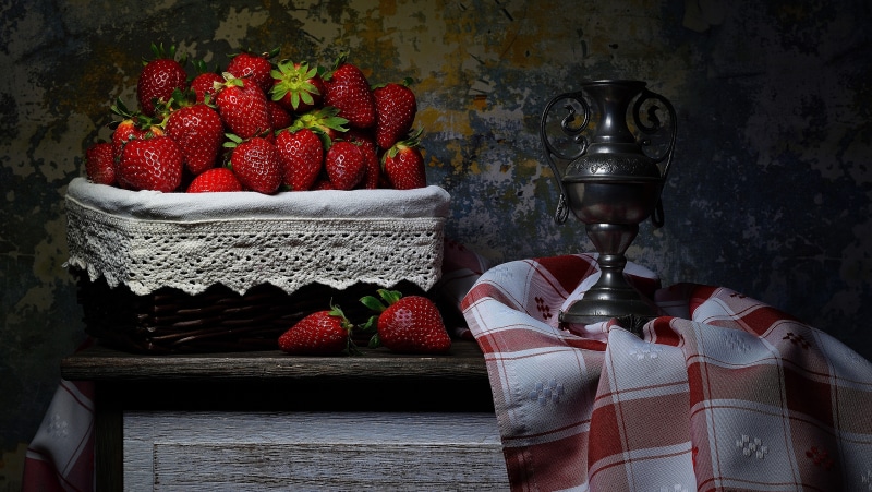 Still-life with strawberries in a wicker basket and a vase