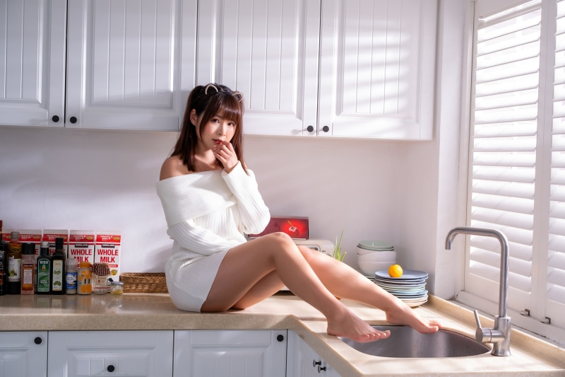 Asian woman in white dress sitting in kitchen