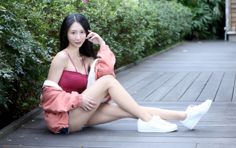 Asian woman in shorts and singlet sitting on boardwalk