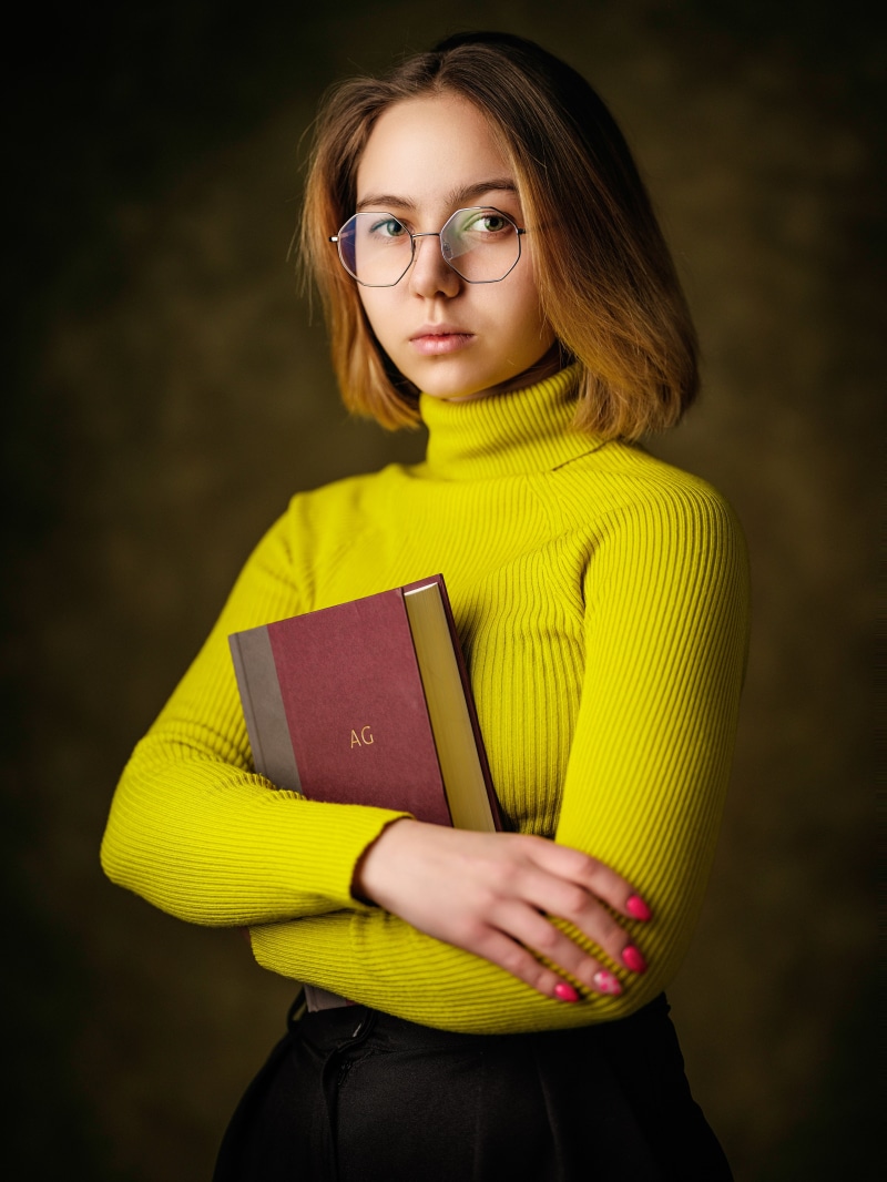 Young woman with glasses holding a book