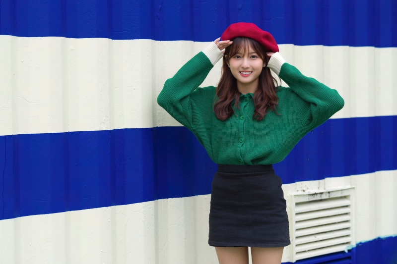 Asian woman wearing a beret and green sweater