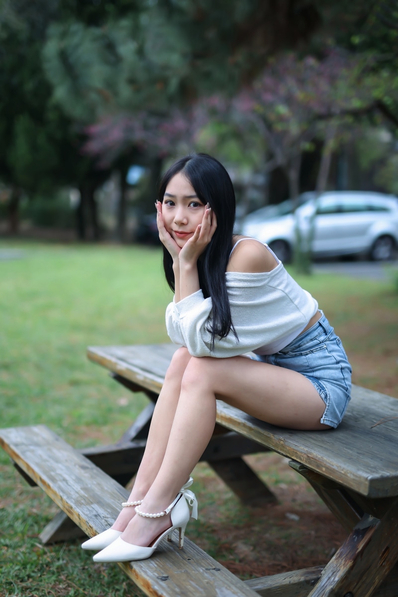 Asian woman sitting on a picnic table outdoors