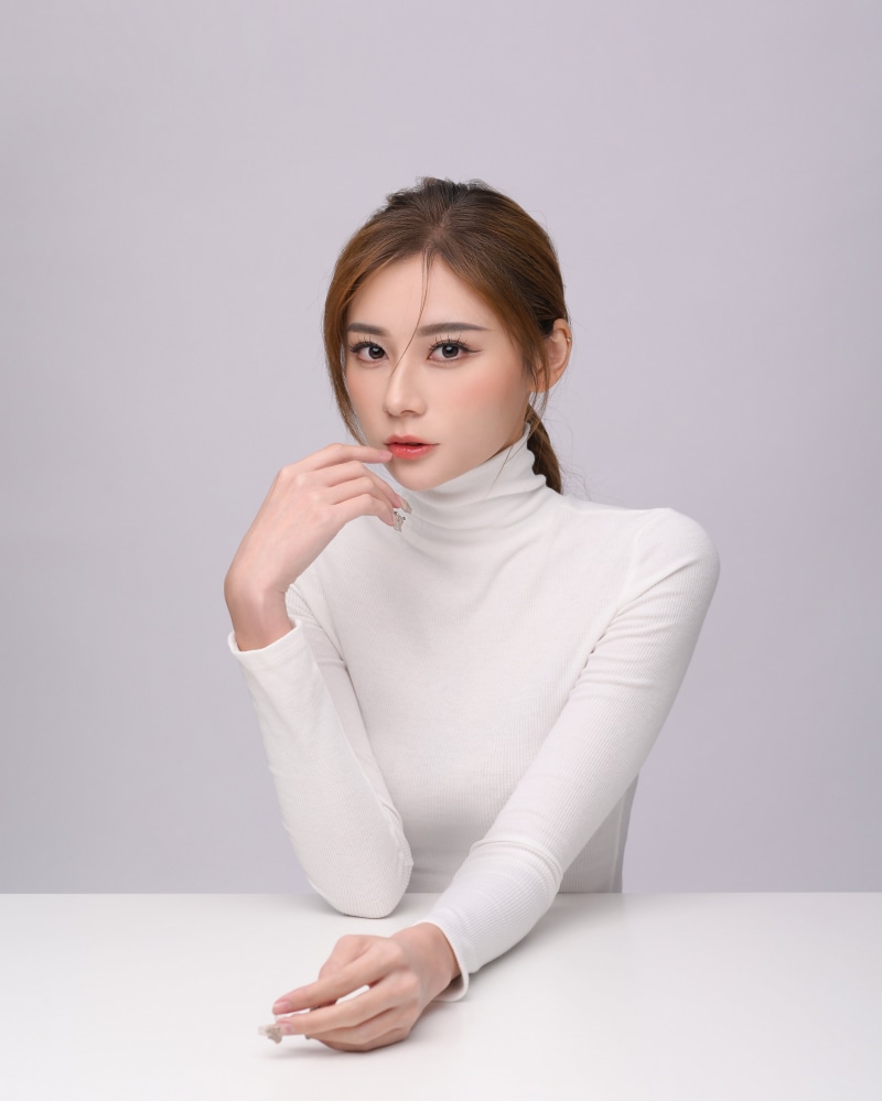Asian woman with brown hair wearing a white turtleneck