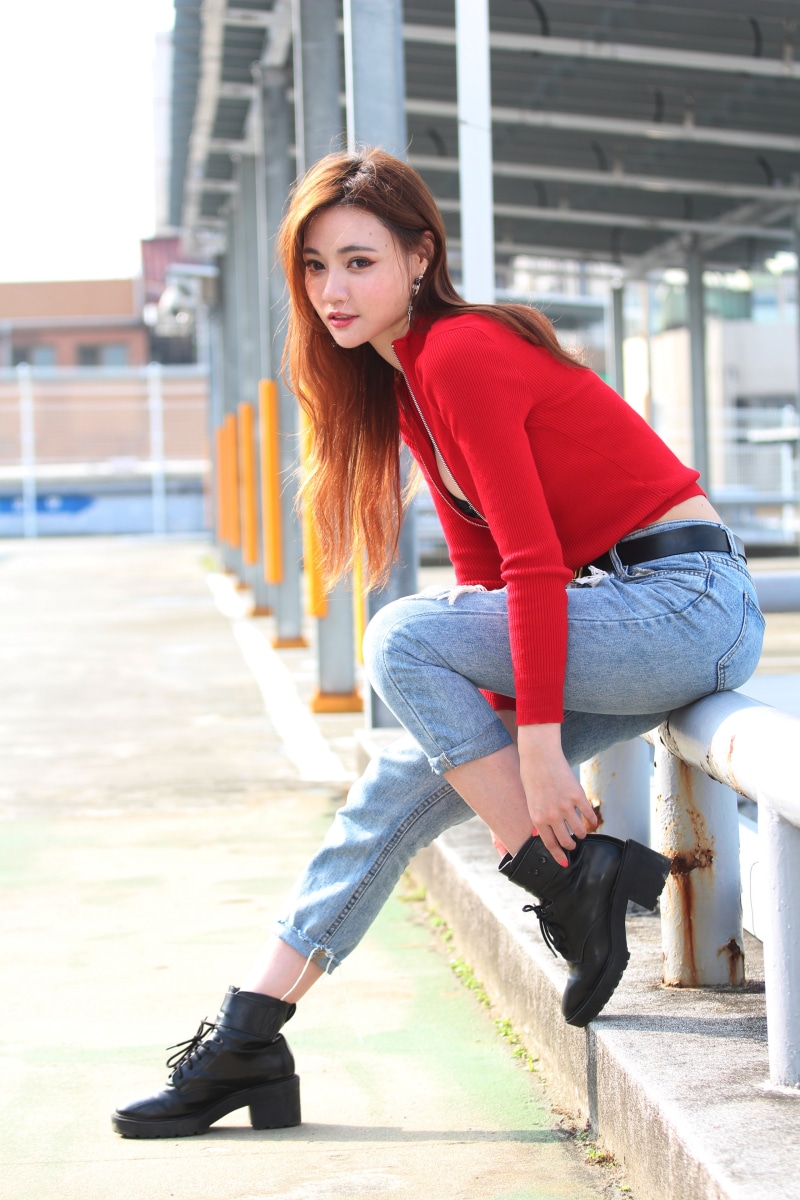 Asian woman in red top and jeans posing outdoors