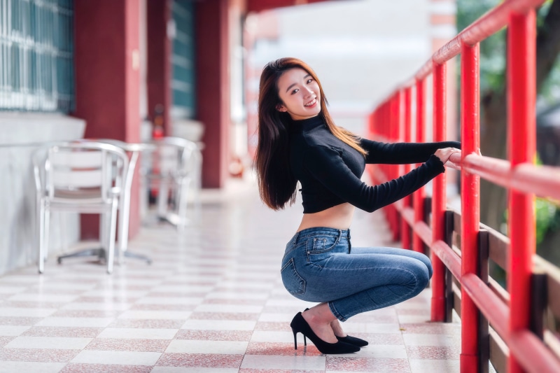 Asian woman in jeans and stilettos posing
