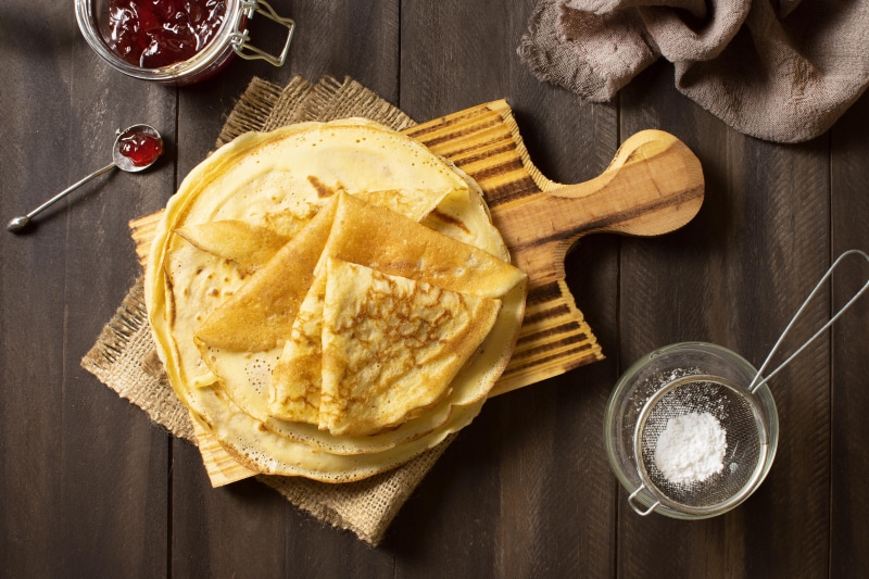 Pancakes with Jam and Powdered Sugar on Cutting Board