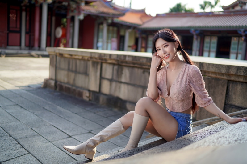 Asian woman sitting on steps wearing shorts and boots