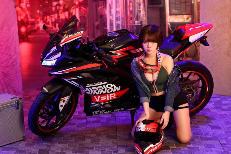 Asian woman in shorts and singlet with Yamaha motorcycle and helmet