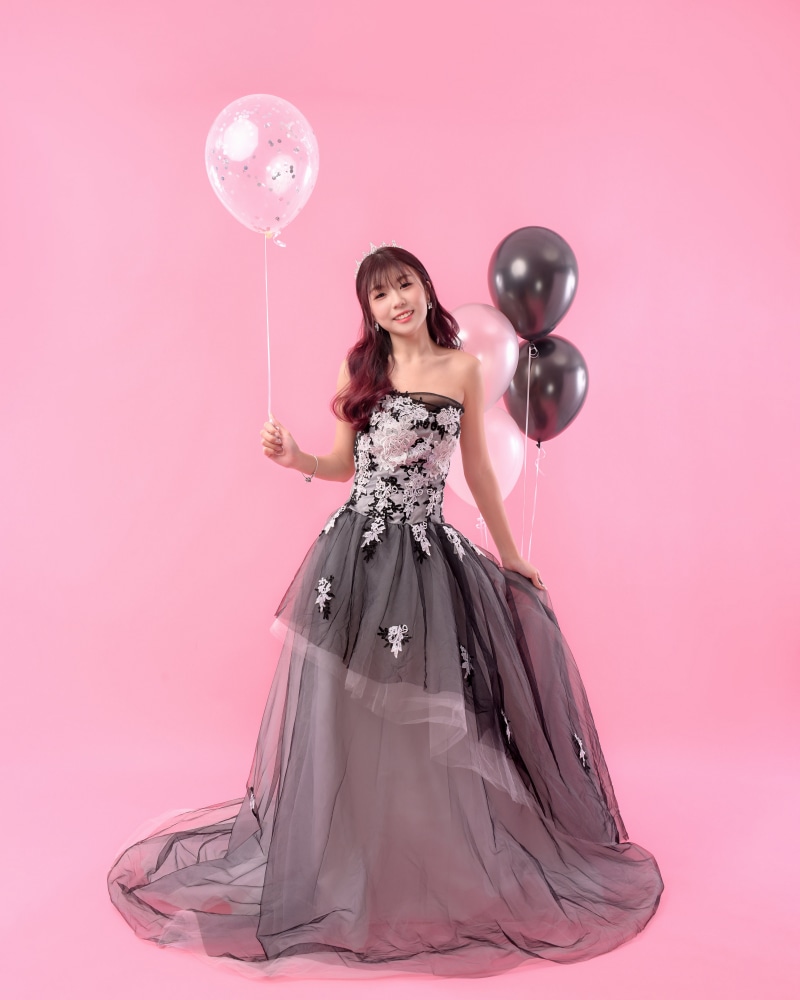 Young Asian woman in a formal dress holding balloons