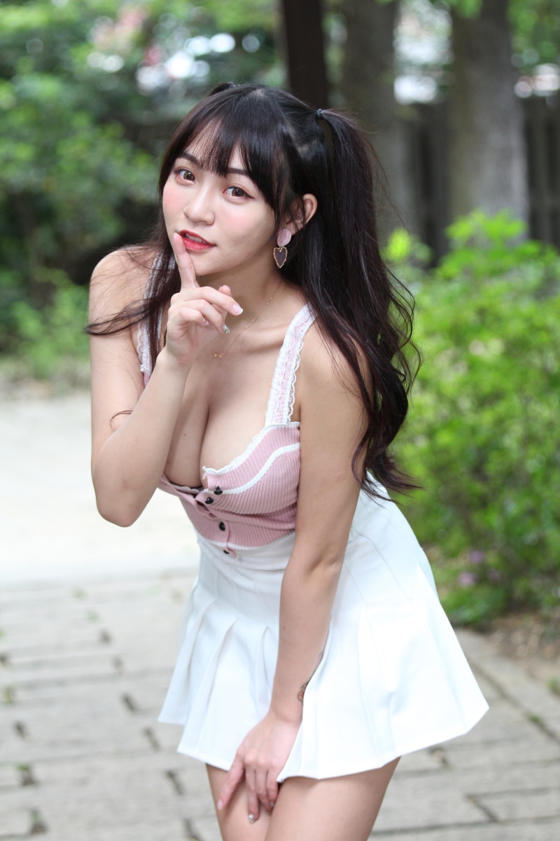 Asian woman in pink and white top and skirt posing outdoors