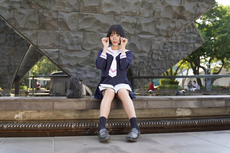 Asian schoolgirl in uniform with glasses sitting with book