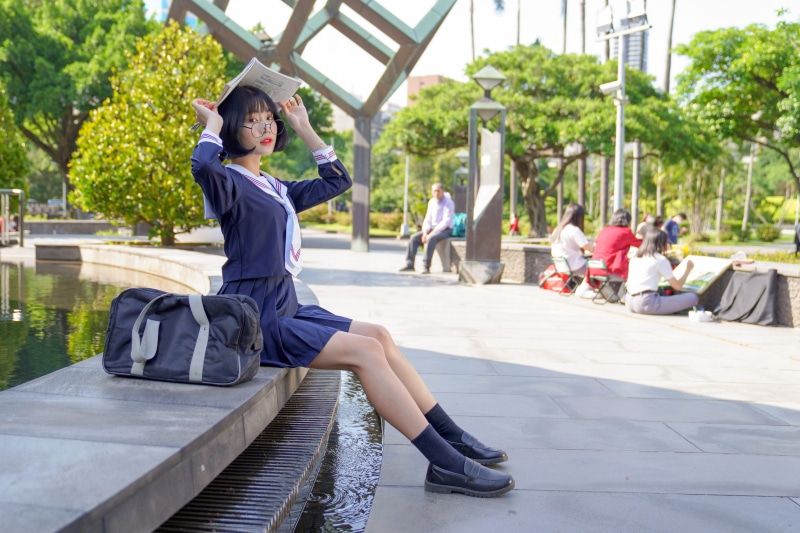 Asian schoolgirl with book on head in park