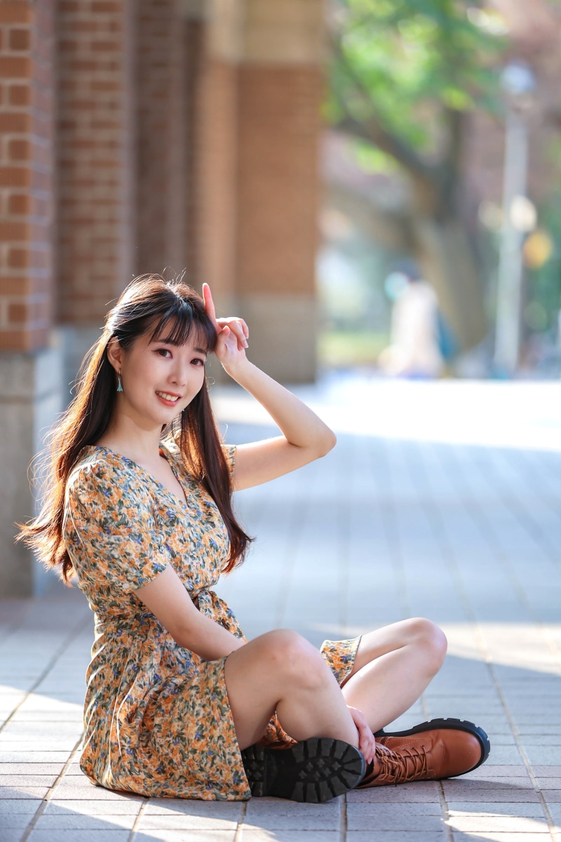 Asian woman in floral dress and boots posing outdoors