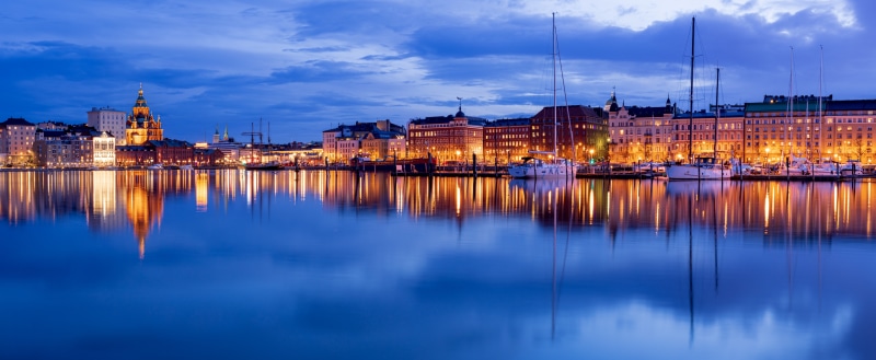 Helsinki waterfront with illuminated buildings and yachts