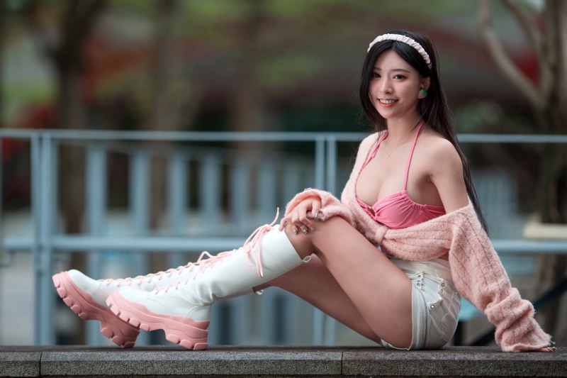 Asian woman wearing pink bikini top, shorts, and white boots
