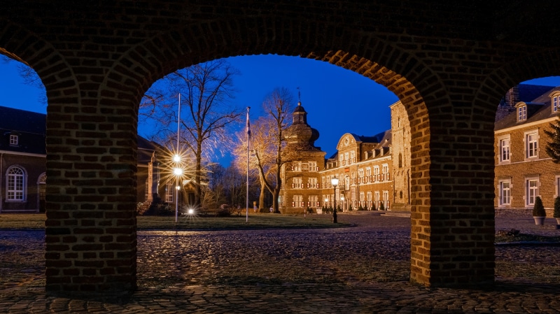 Abbey Klosterrath at night through a brick archway
