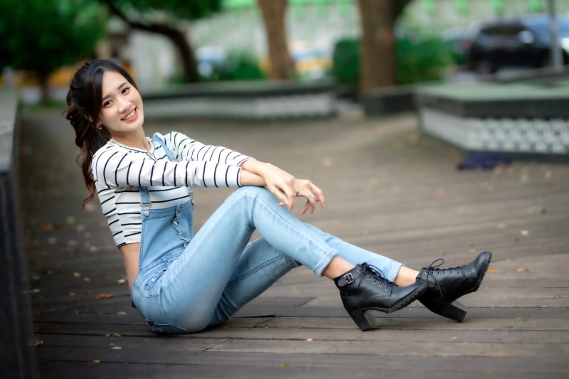 Asian woman in jeans and boots sitting