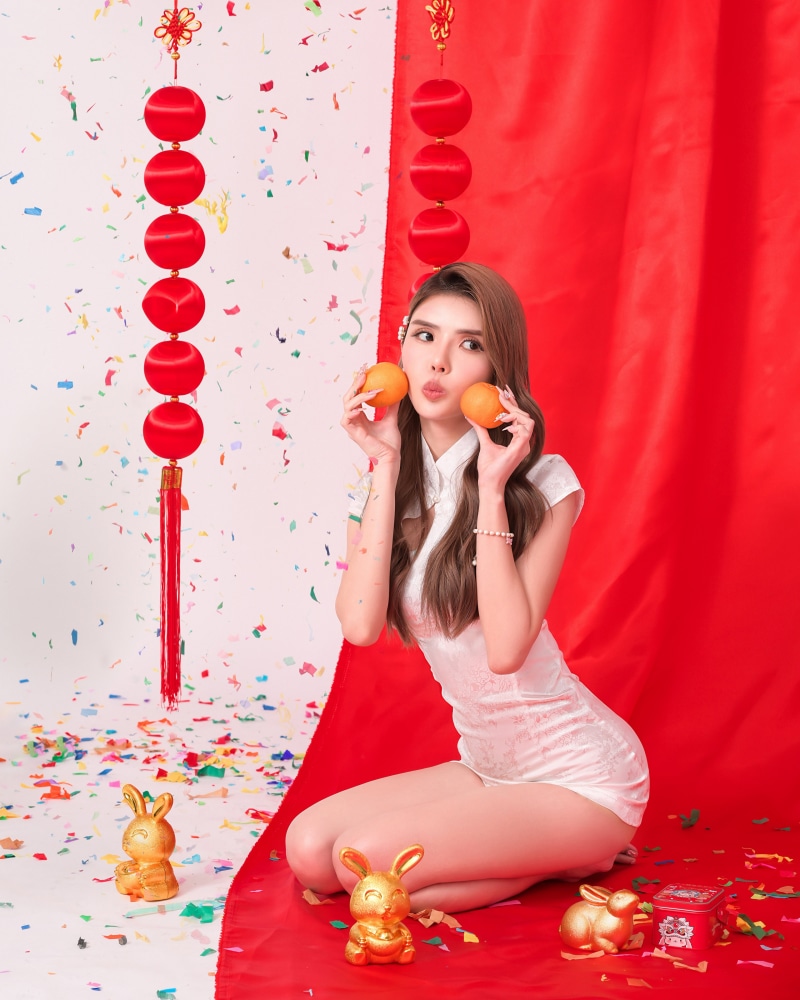 Woman in Cheongsam holding oranges with rabbit figurines