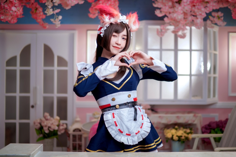 Asian girl in maid cosplay making heart gesture