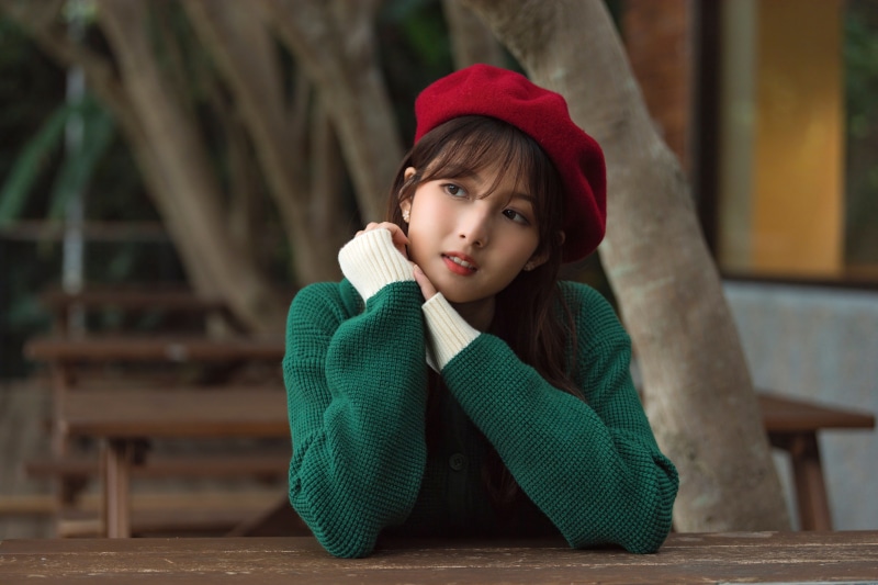 Asian woman wearing a red beret and green sweater