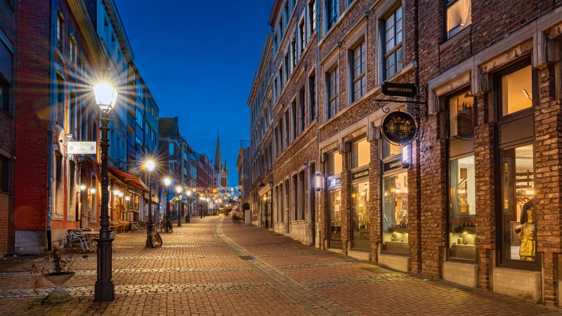 Street lights on a cobblestone street in Aachen, Germany at dusk