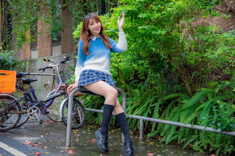 Asian woman in sweater and skirt waving