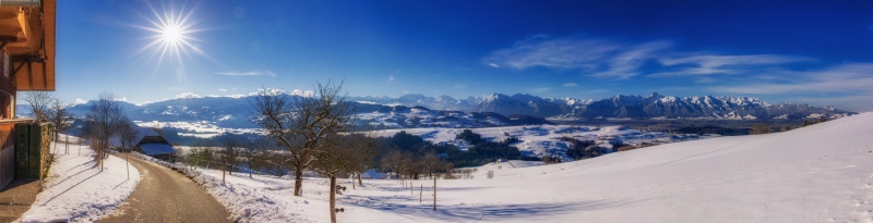 Panorama of snow-covered Alps in Switzerland with sun