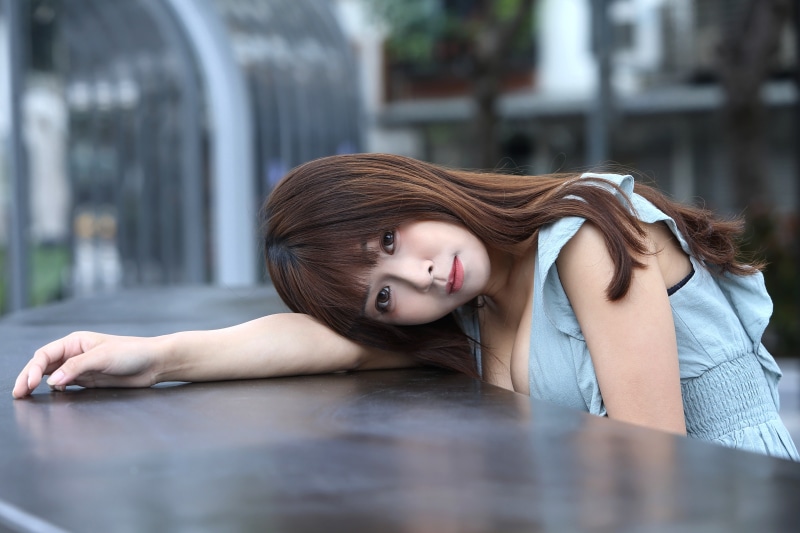 Asian woman with brown hair resting her head on her arm